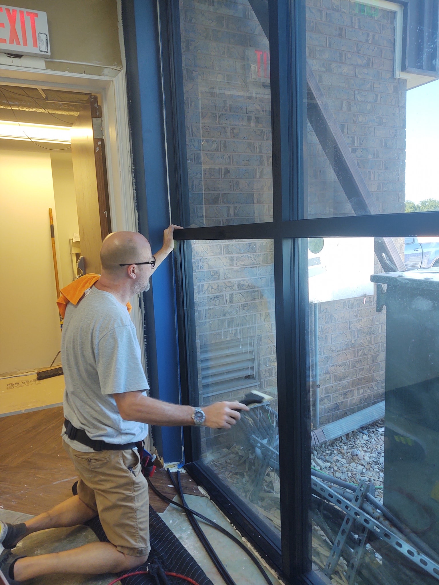Installer applying tint to commercial building window, interior view