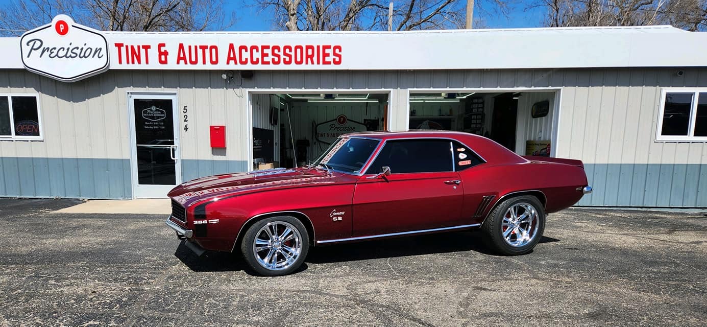 Dark red 1969 Camaro SS 396 with window tint, classic muscle car in front of shop