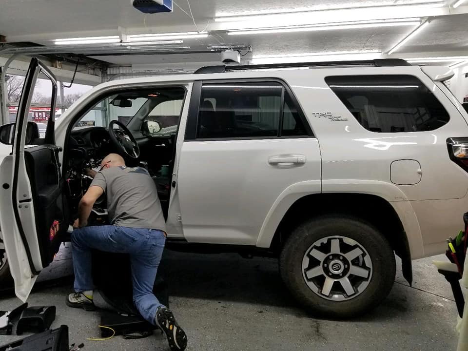 Installer working inside Toyota 4Runner TRD with door panel removed during remote start installation