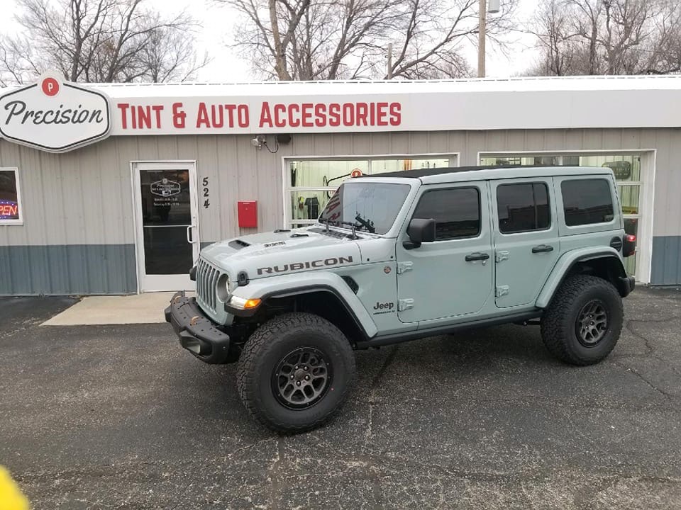 Sage green Jeep Wrangler Rubicon with dark window tint in front of Precision Tint