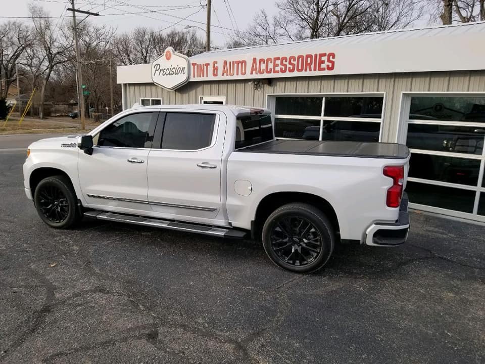 White Chevy Silverado crew cab with dark window tint in front of shop